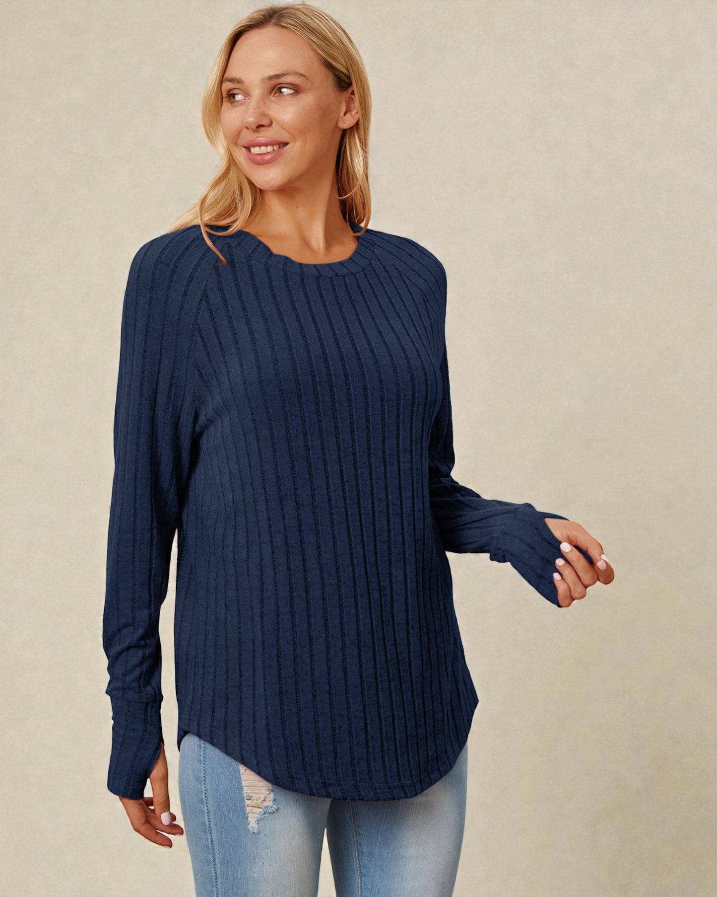 Woman wearing a navy blue ribbed sweater against a beige background