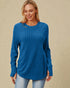 Woman wearing a blue ribbed sweater against a beige background
