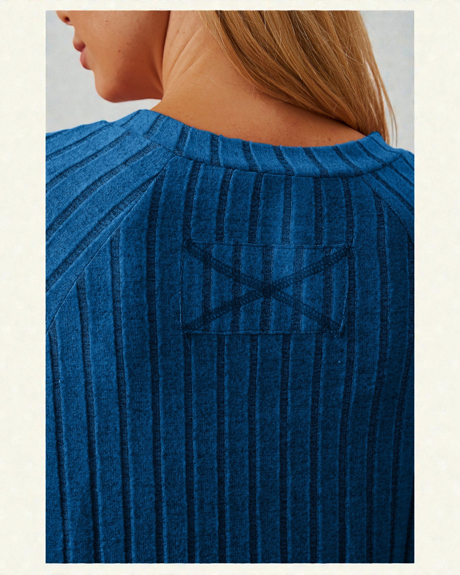 Blue ribbed sweater with a pocket on a neutral background