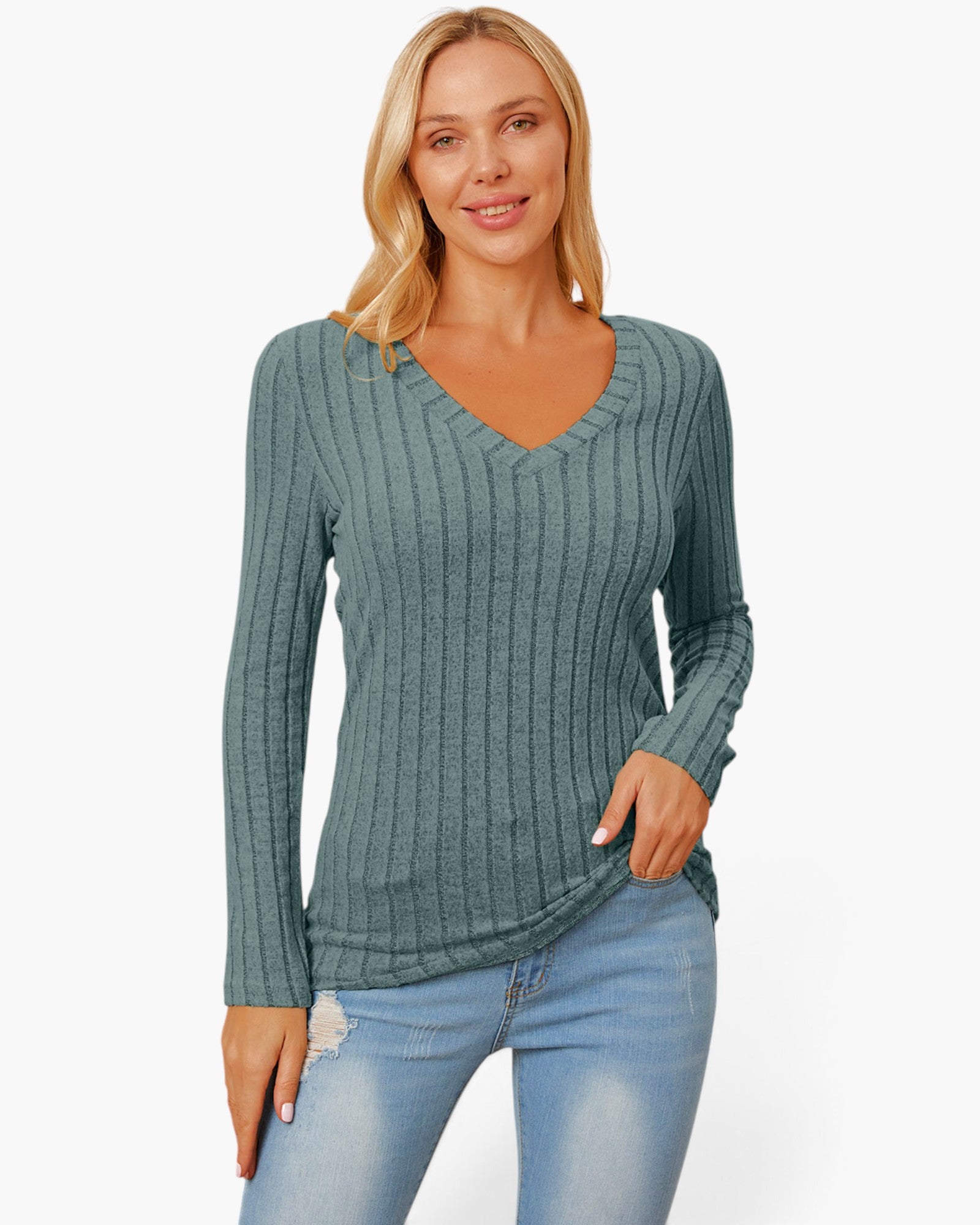 A woman wearing a ribbed long-sleeve V-neck sweater in a muted teal-green color, paired with light-wash blue jeans, against a plain white studio background.