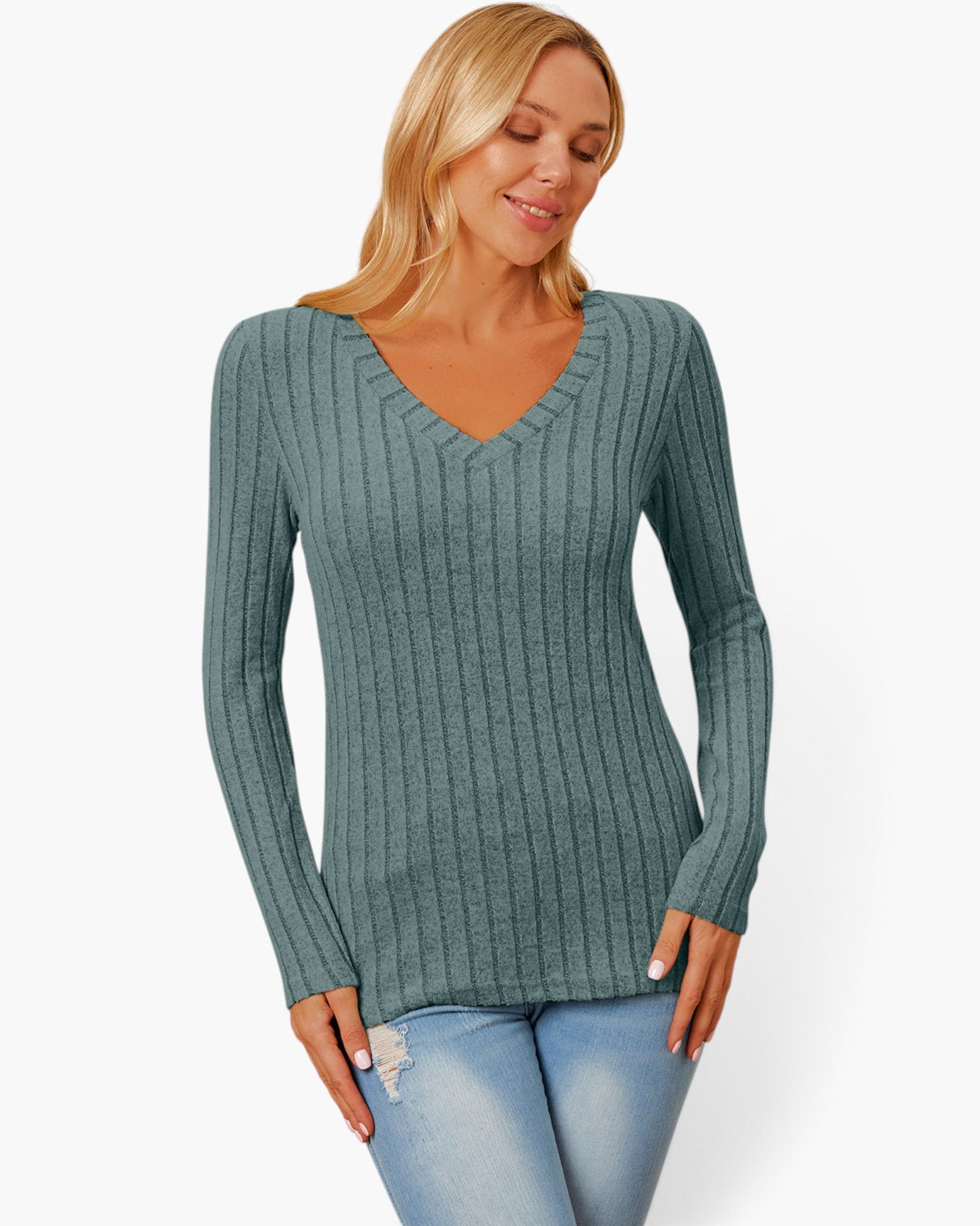 A woman wearing a ribbed long-sleeve V-neck sweater in a muted teal-green color, paired with light blue jeans, against a plain white background.