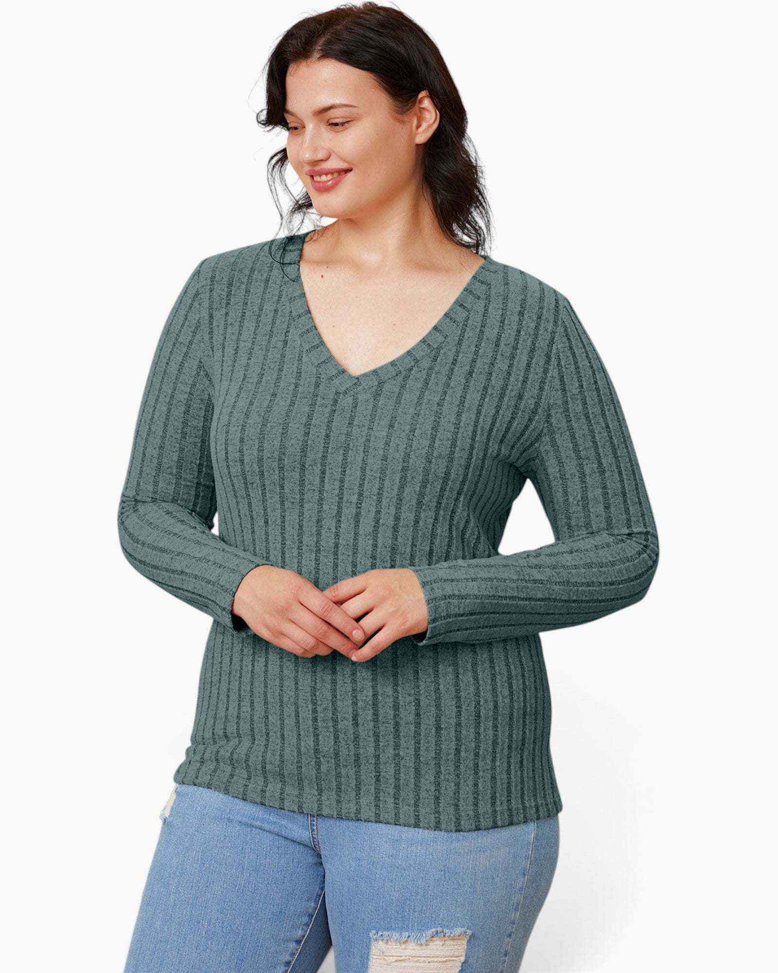 A woman wearing a ribbed long-sleeve V-neck sweater in a muted sage green color, paired with light blue jeans, against a plain white studio background.