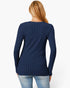 A woman viewed from the back wearing a navy blue ribbed long-sleeve top and light blue jeans against a plain white background.