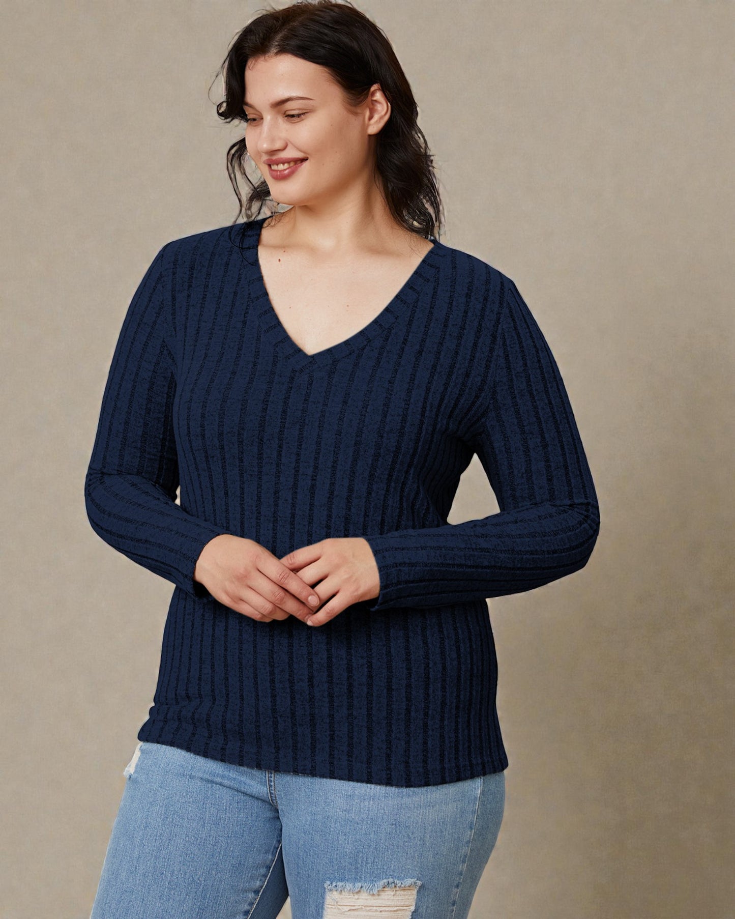 Woman wearing a navy blue ribbed sweater against a beige background
