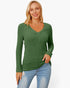 A woman wearing a green ribbed long-sleeve V-neck sweater and light blue jeans, standing against a plain white studio background.