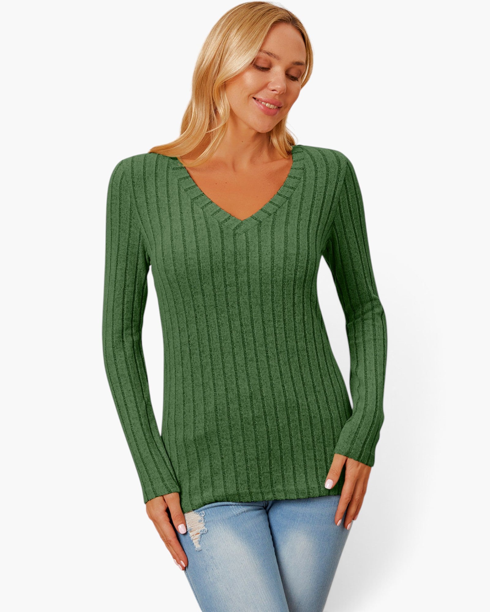 A woman wearing a green ribbed long-sleeve V-neck sweater and light blue jeans, standing against a plain white studio background.