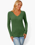 A woman wearing a green ribbed long-sleeve V-neck sweater and light blue jeans, standing against a plain white studio background.
