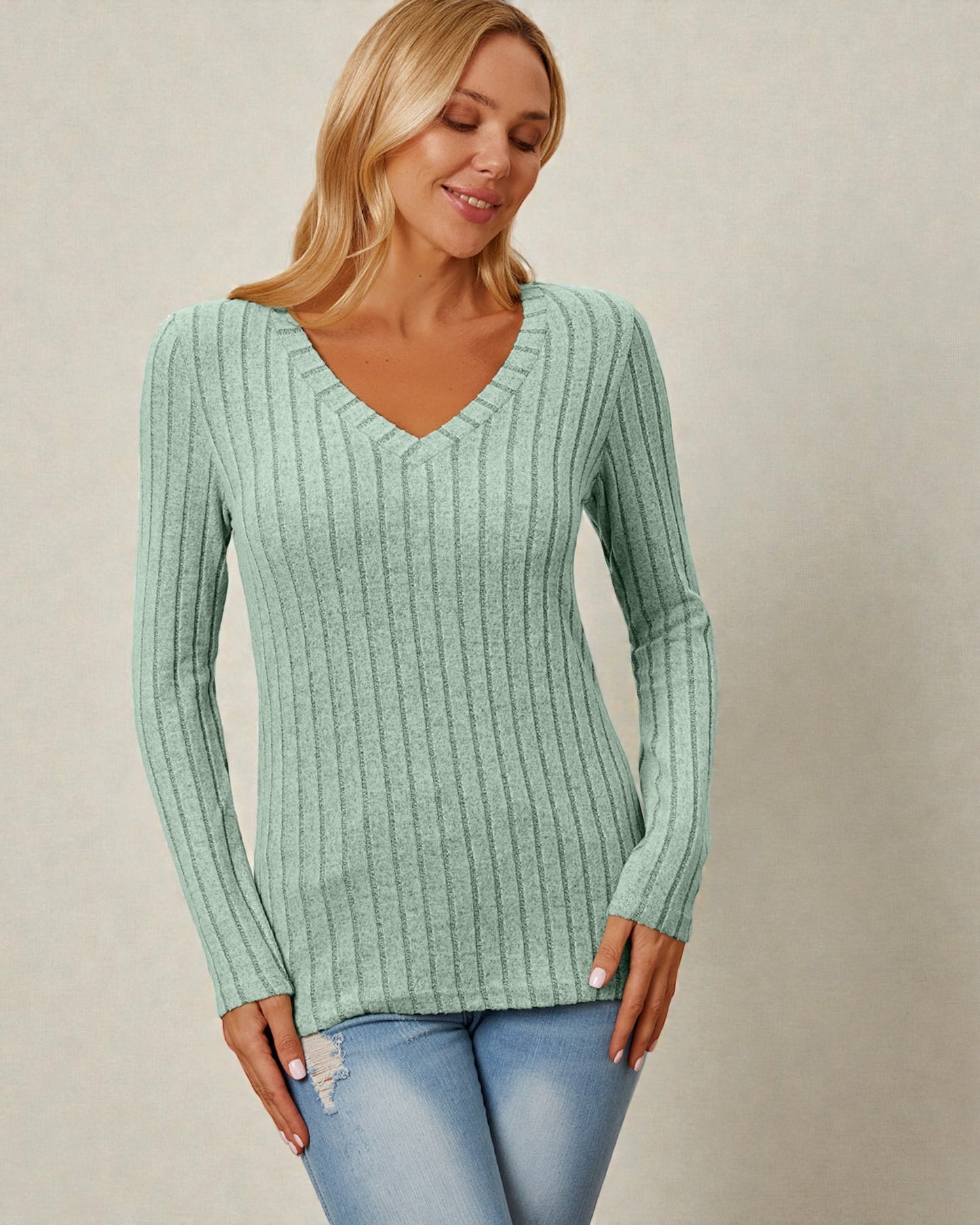 Woman wearing a green ribbed sweater against a beige background