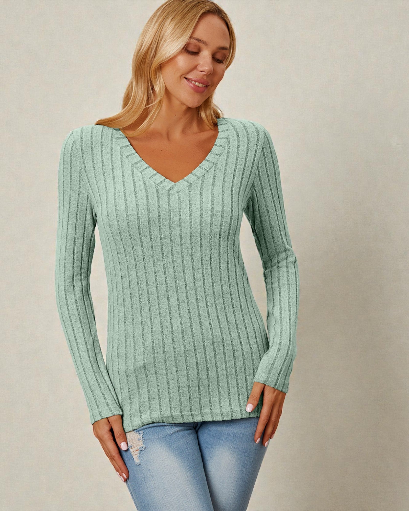 Woman wearing a green ribbed sweater against a beige background