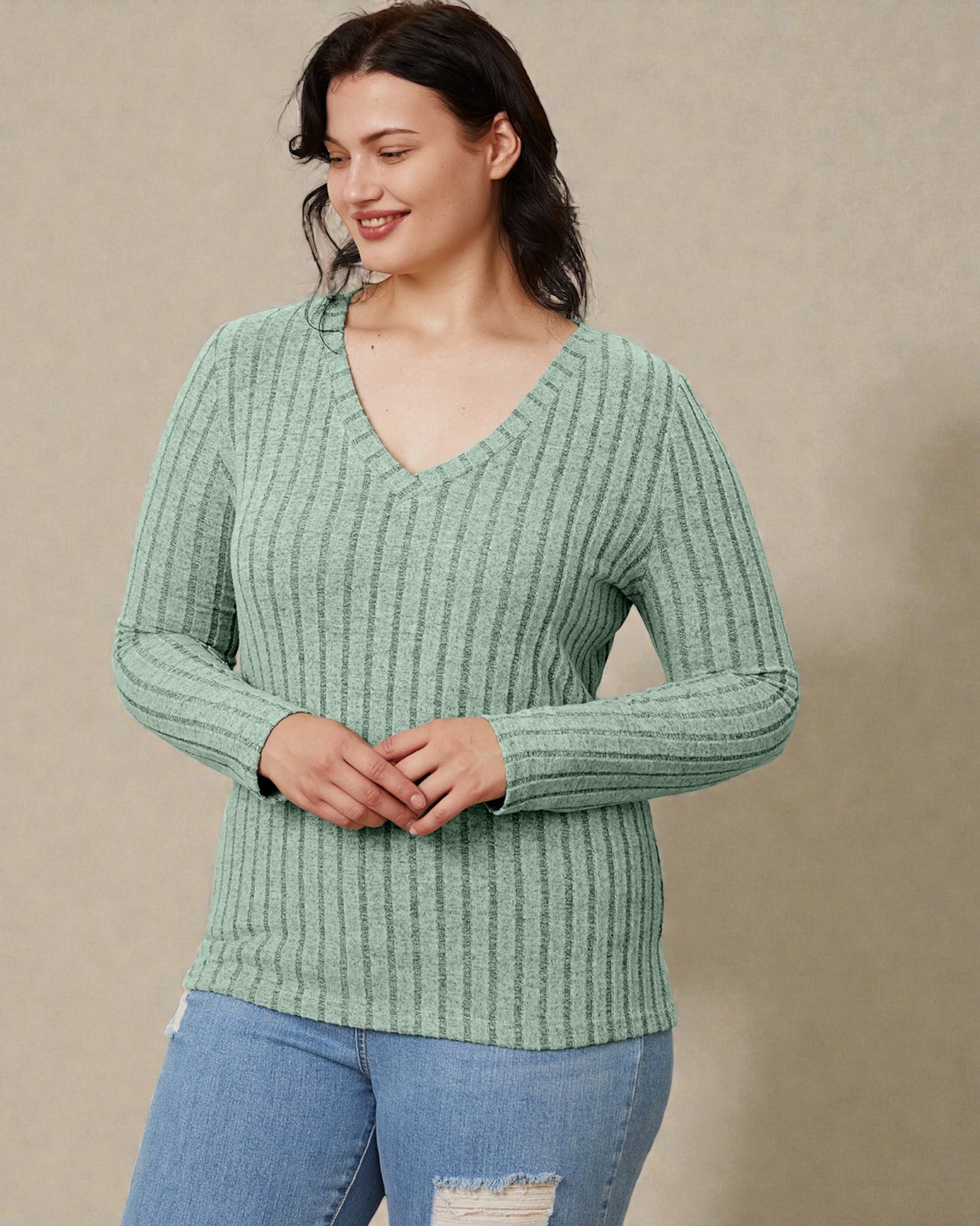 Woman wearing a green ribbed sweater against a beige background