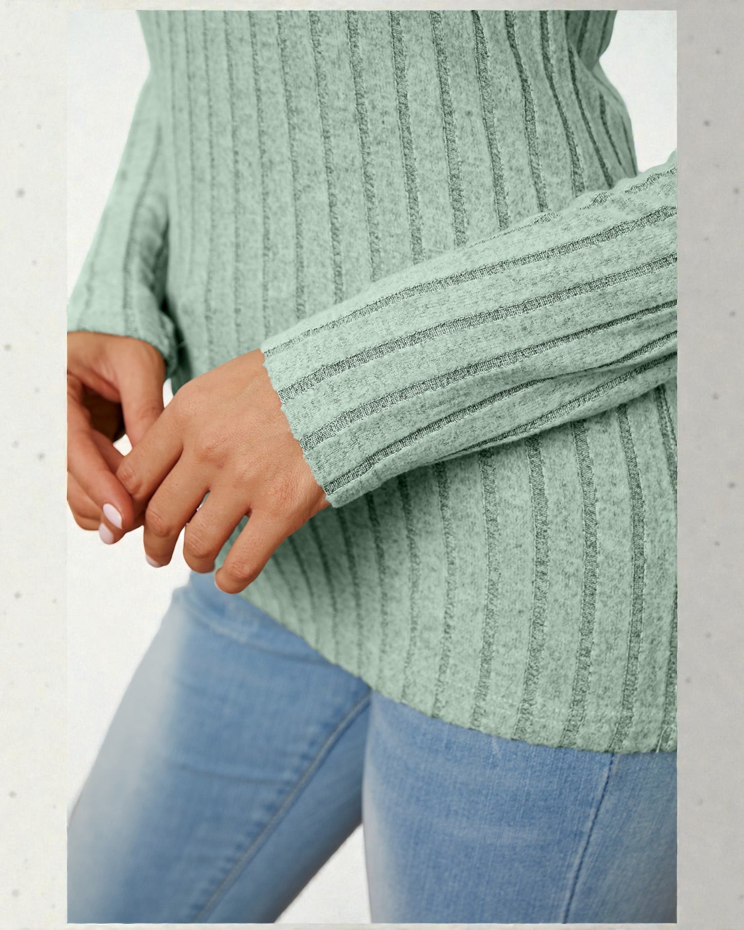 Green ribbed sweater and blue jeans on a light gray background