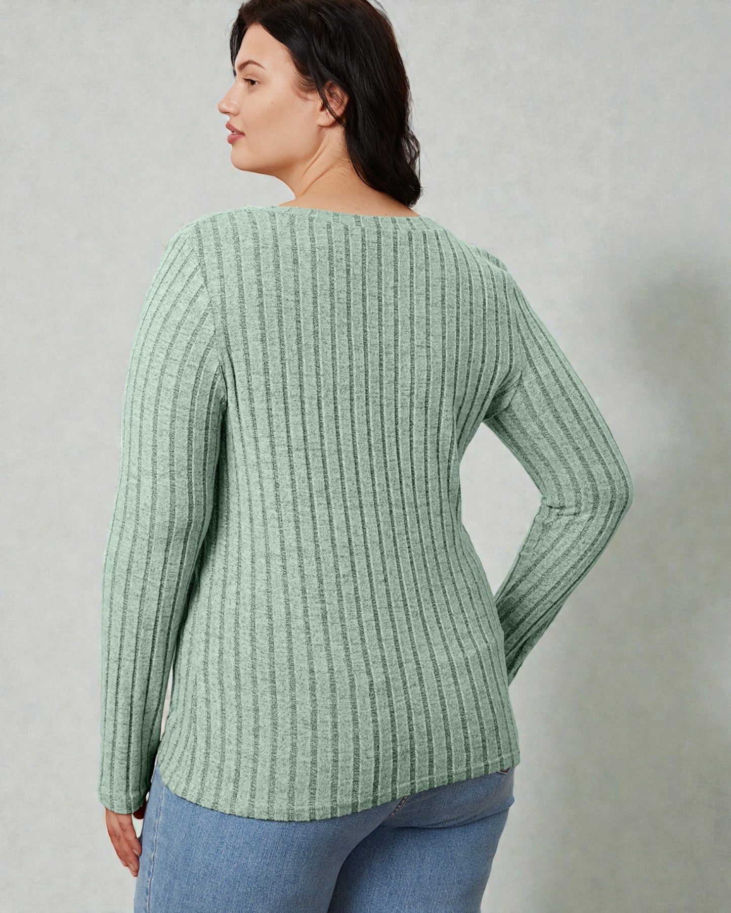 Woman wearing a green ribbed sweater against a plain background