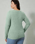 Woman wearing a green ribbed sweater against a plain background