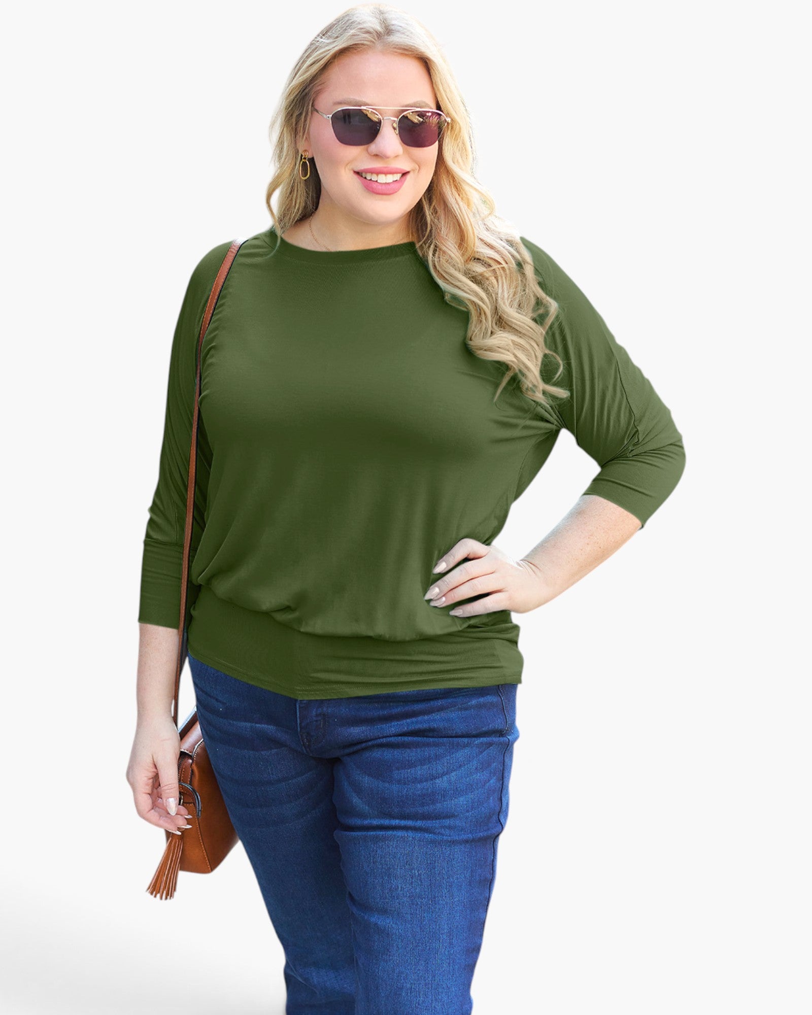A woman modeling a three-quarter sleeve olive green top with a crew neck, paired with blue jeans and a small brown crossbody bag, against a plain white background.