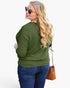 A woman with long blonde wavy hair, wearing aviator sunglasses, an olive green long-sleeve top, and blue jeans, carrying a brown leather shoulder bag against a white studio background.