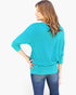 A woman shown from the back wearing a bright turquoise three-quarter sleeve top and blue jeans against a plain white background.