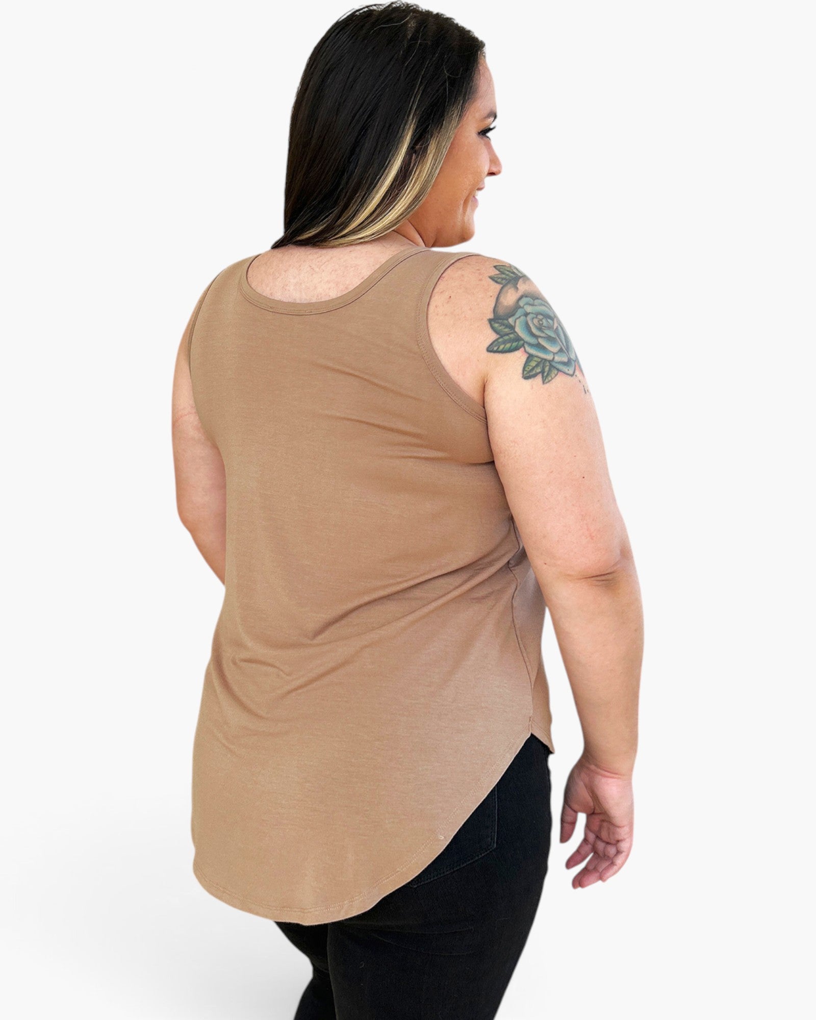 A woman shown from the back wearing a sleeveless, scoop-neck tan top and black pants against a plain white studio background.