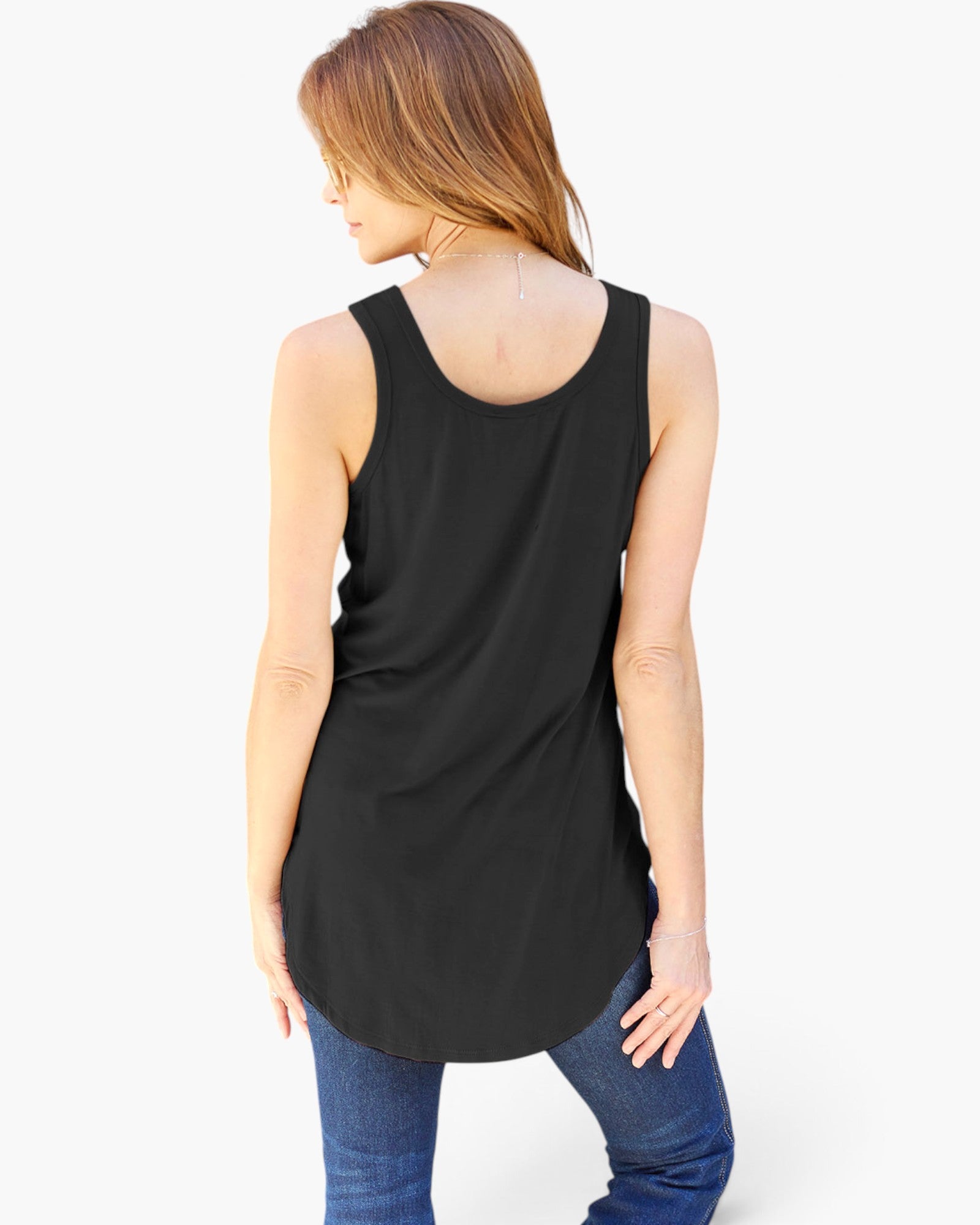 A woman shown from the back wearing a black sleeveless scoop-neck tunic top and blue jeans against a plain white studio background.