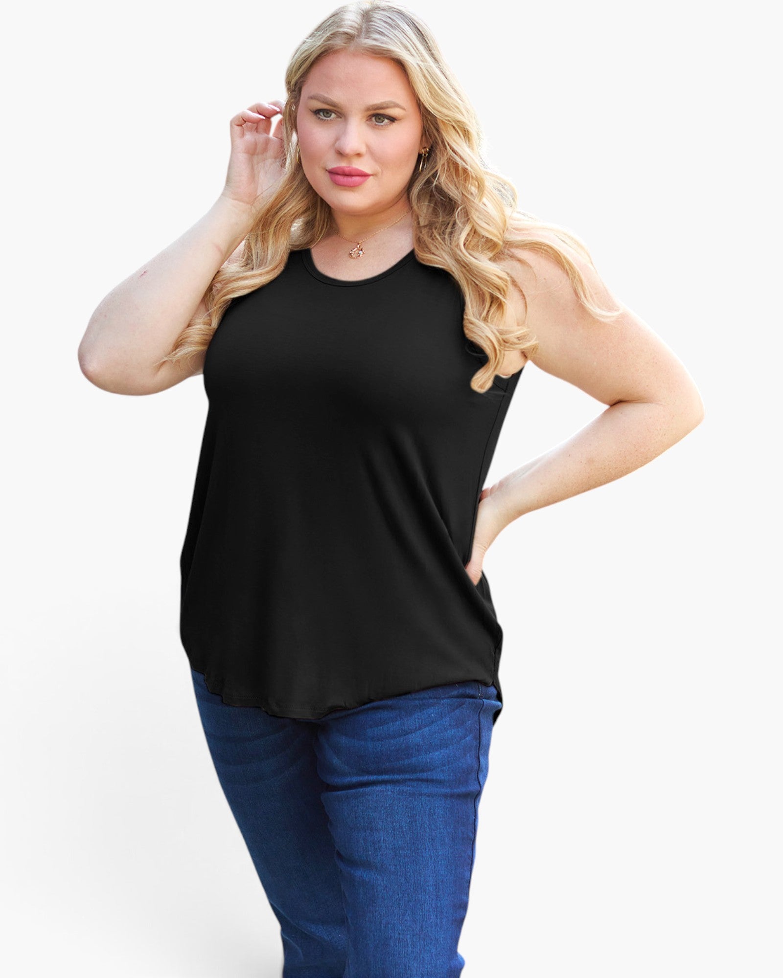 A woman modeling a sleeveless black scoop-neck top with blue jeans against a plain white studio background.
