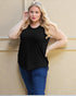 Woman wearing a black sleeveless top and blue jeans against a beige wall.