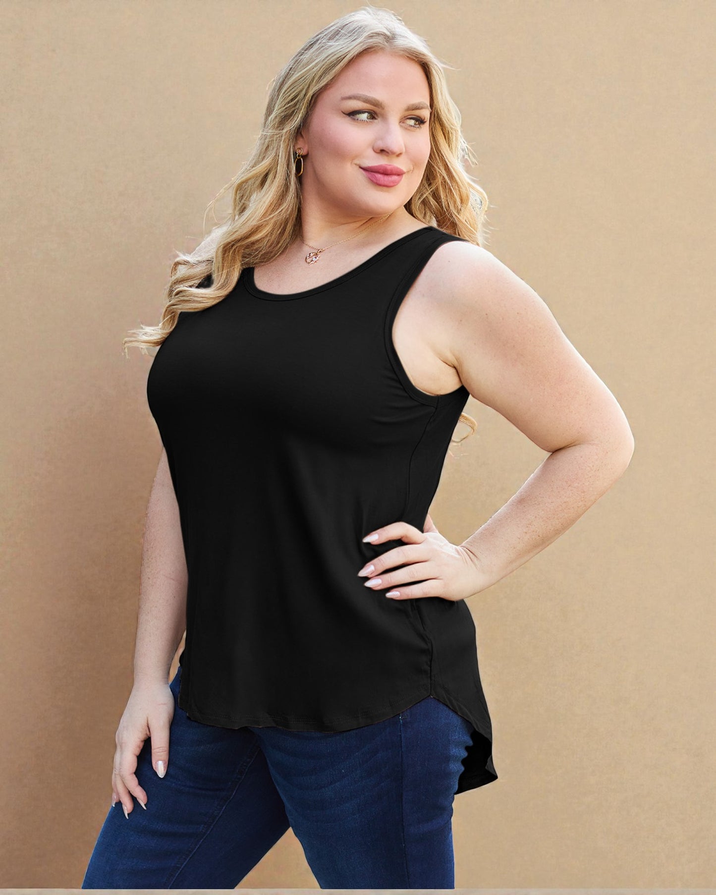 Woman wearing a black sleeveless top and blue jeans against a beige background
