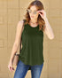 Woman wearing a green sleeveless top and blue jeans against a beige brick wall.