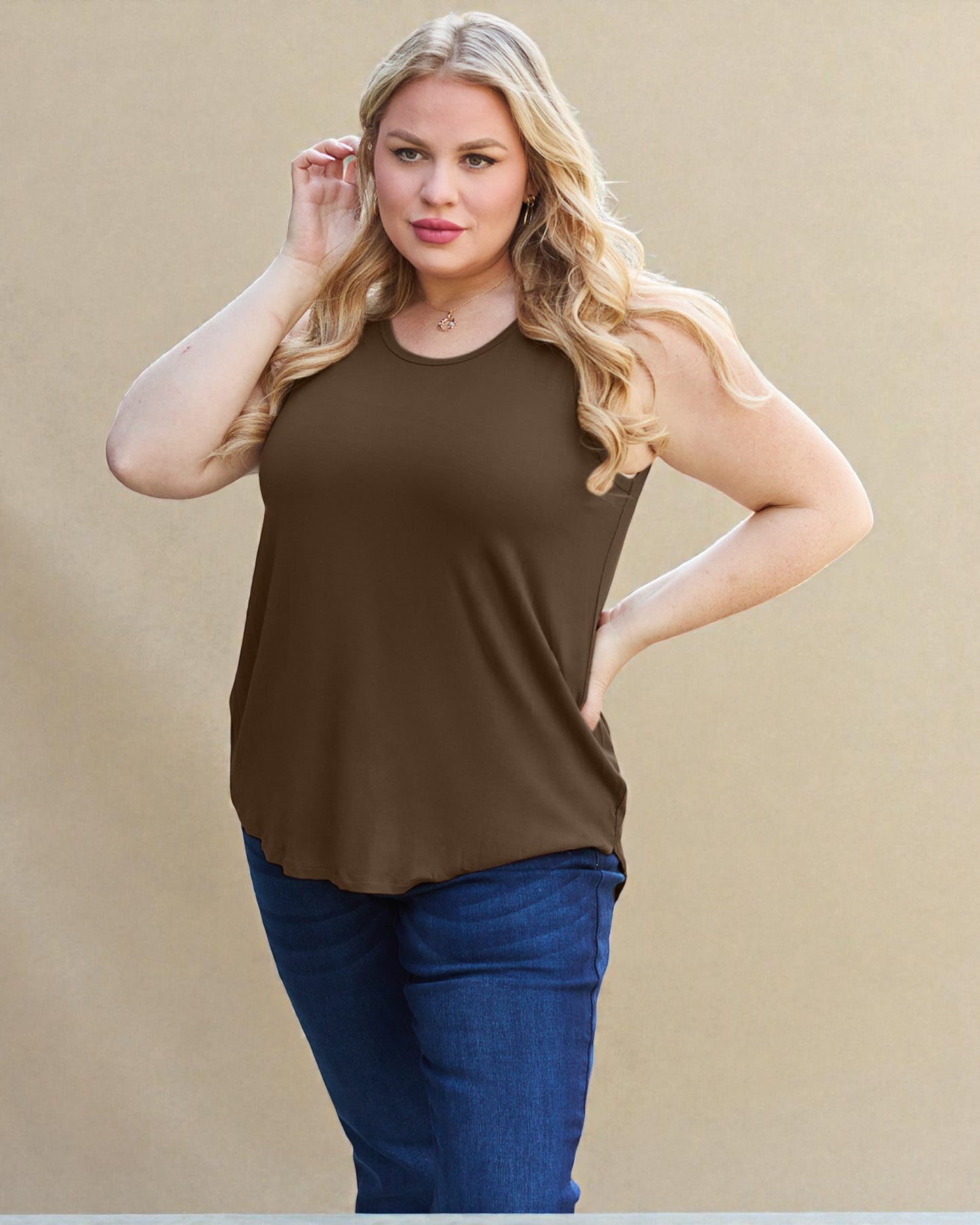 Woman wearing a brown sleeveless top and blue jeans against a beige background