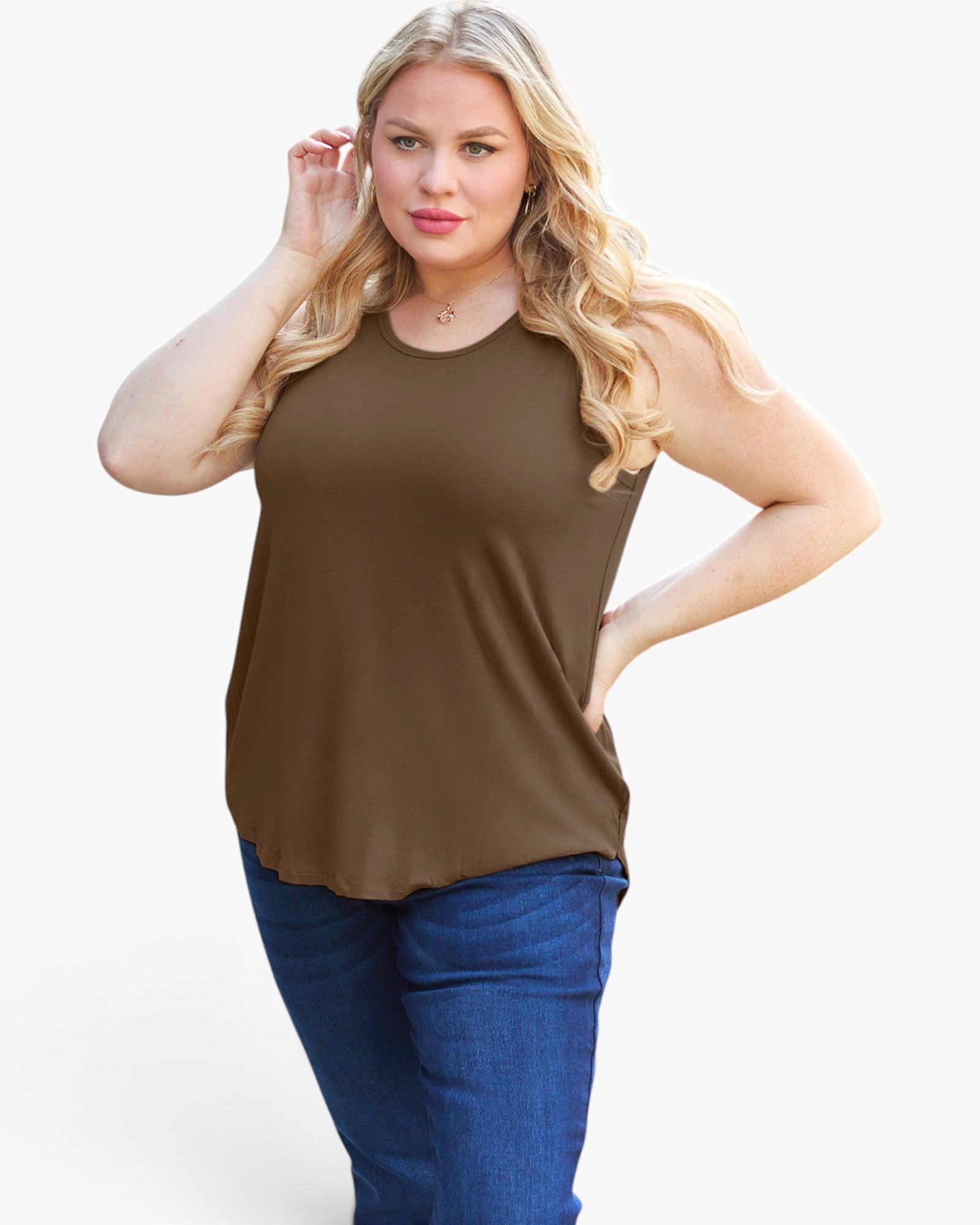A woman modeling a sleeveless brown top with blue jeans against a plain light gray studio background.