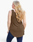 A woman with long blonde wavy hair is shown from the back wearing a sleeveless brown tunic top and dark blue jeans against a plain white background.