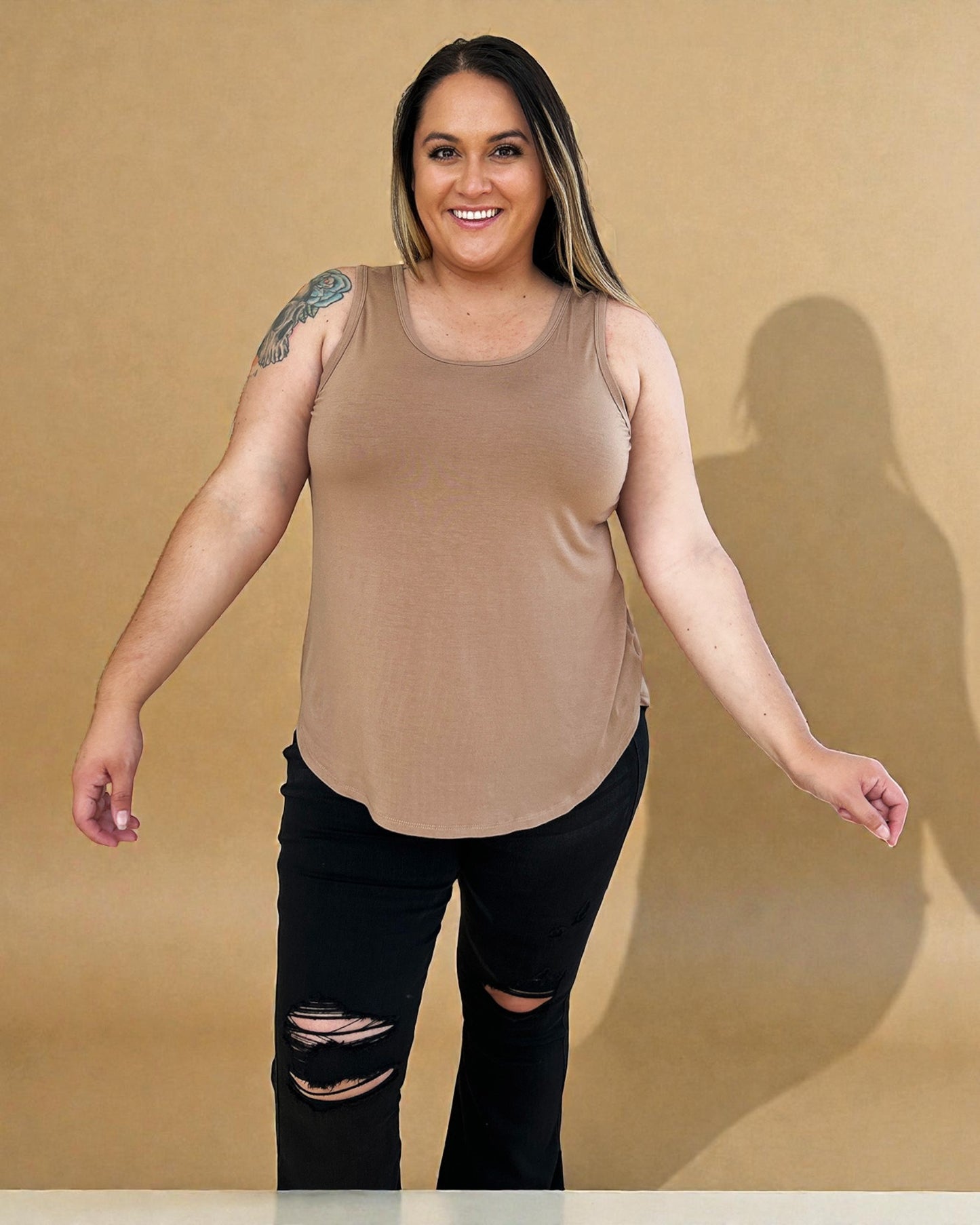 Woman wearing a brown tank top and black pants against a beige background