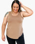 A woman modeling a scoop-neck, sleeveless tank top in a light tan color, paired with black pants, against a plain white background.
