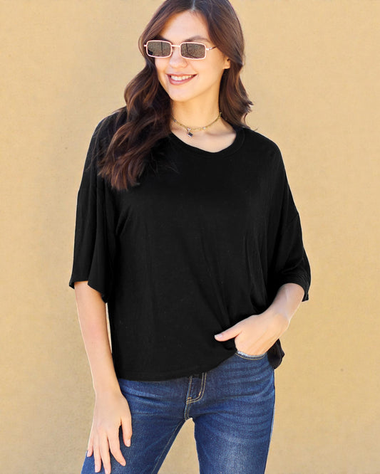 Woman wearing a black top and blue jeans against a beige background
