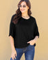 Woman wearing a black top and blue jeans against a beige background