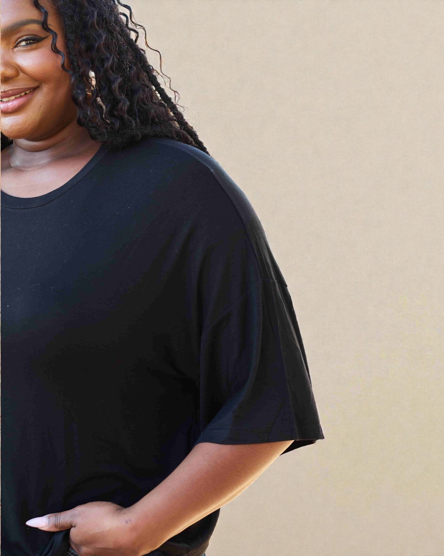 Person wearing a black t-shirt against a beige background