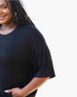 A close-up of a woman wearing a black oversized short-sleeve t-shirt against a plain white background.