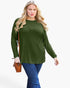 A woman modeling a long-sleeve crewneck top in olive green, paired with blue jeans and carrying a small brown crossbody bag, against a plain light gray background.