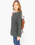 A woman modeling a dark gray long-sleeve top with blue jeans and a brown woven backpack, photographed against a plain white studio background.