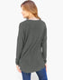 A woman wearing a dark gray long-sleeve tunic top with blue jeans, shown from a back-three-quarter view against a plain white background.