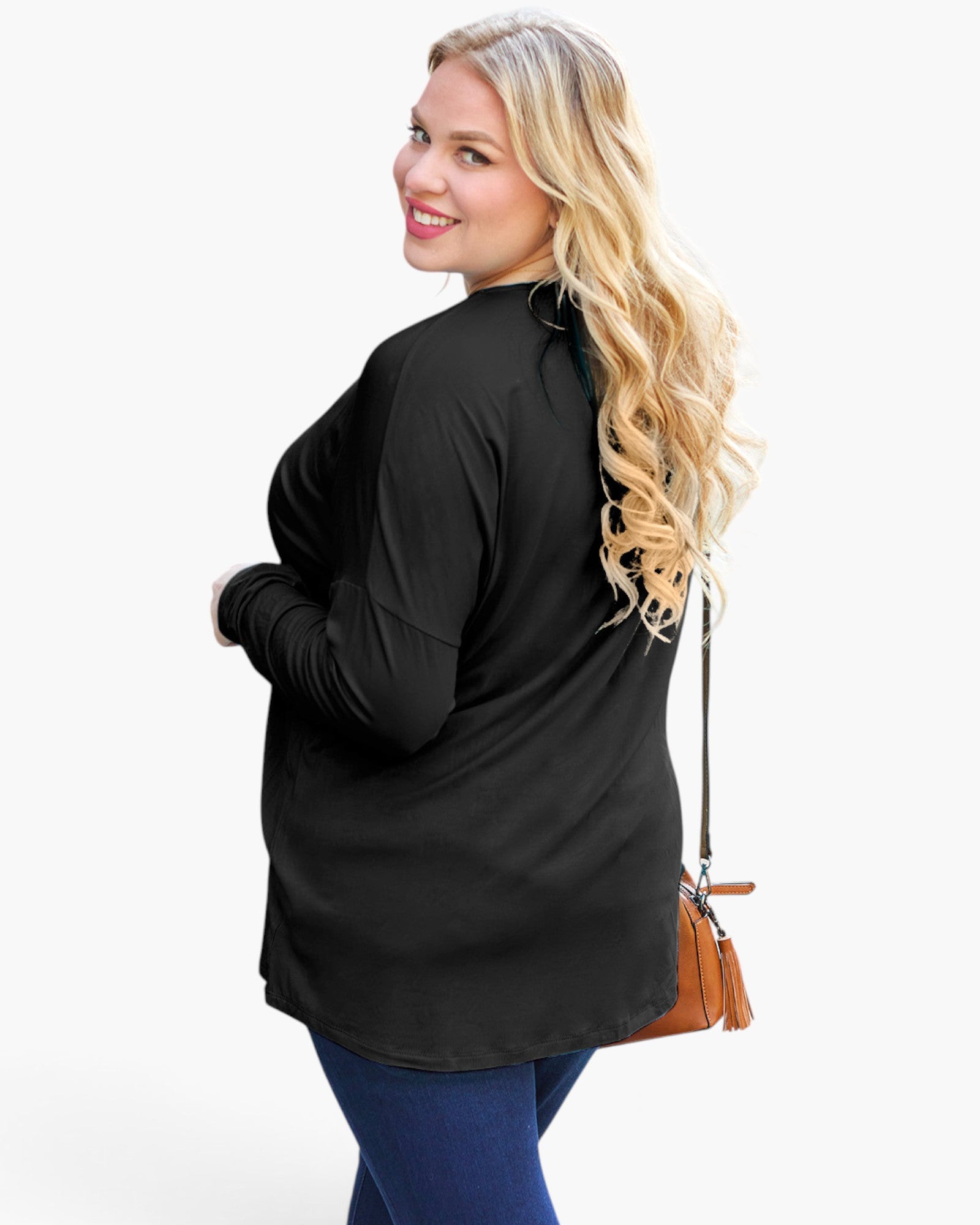A woman with long blonde hair is shown from the back wearing a black long-sleeve tunic top and blue jeans, holding a brown crossbody purse against a plain white studio background.