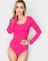 Woman wearing a bright pink long-sleeve swimsuit against a white background