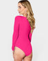 Woman wearing a bright pink swimsuit with long sleeves on a white background
