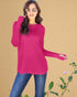 Woman wearing a bright pink long-sleeve top and blue jeans against a beige background