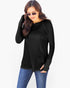A woman wearing a black long-sleeve top with a relaxed fit, raglan sleeves, and a small V-neckline, paired with blue jeans against a plain white background.