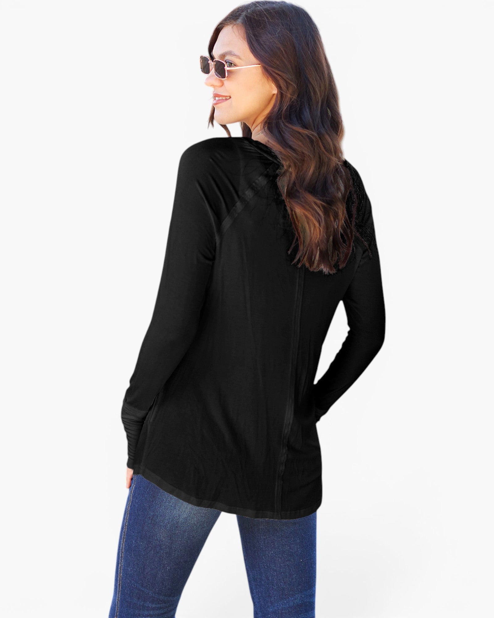 A woman wearing a black long-sleeve hooded top and blue jeans, shown from a back-three-quarter angle against a plain white studio background.