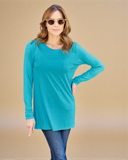 Woman wearing a turquoise long-sleeve top and sunglasses against a beige background