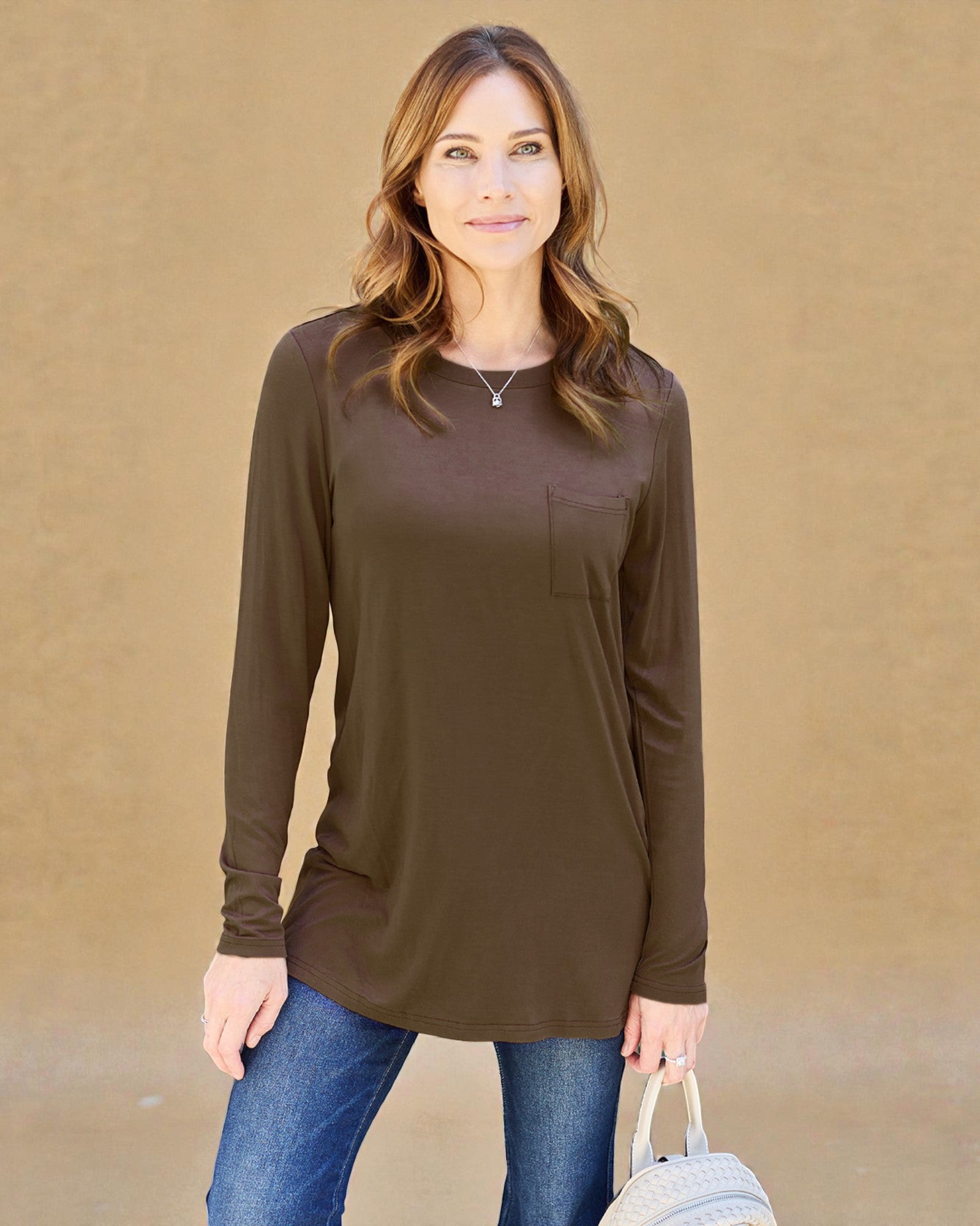 Woman wearing a brown long-sleeve top against a beige background