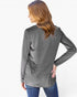 A woman with long brown hair is shown from the back wearing a heather gray long-sleeve top and blue jeans against a plain white background.