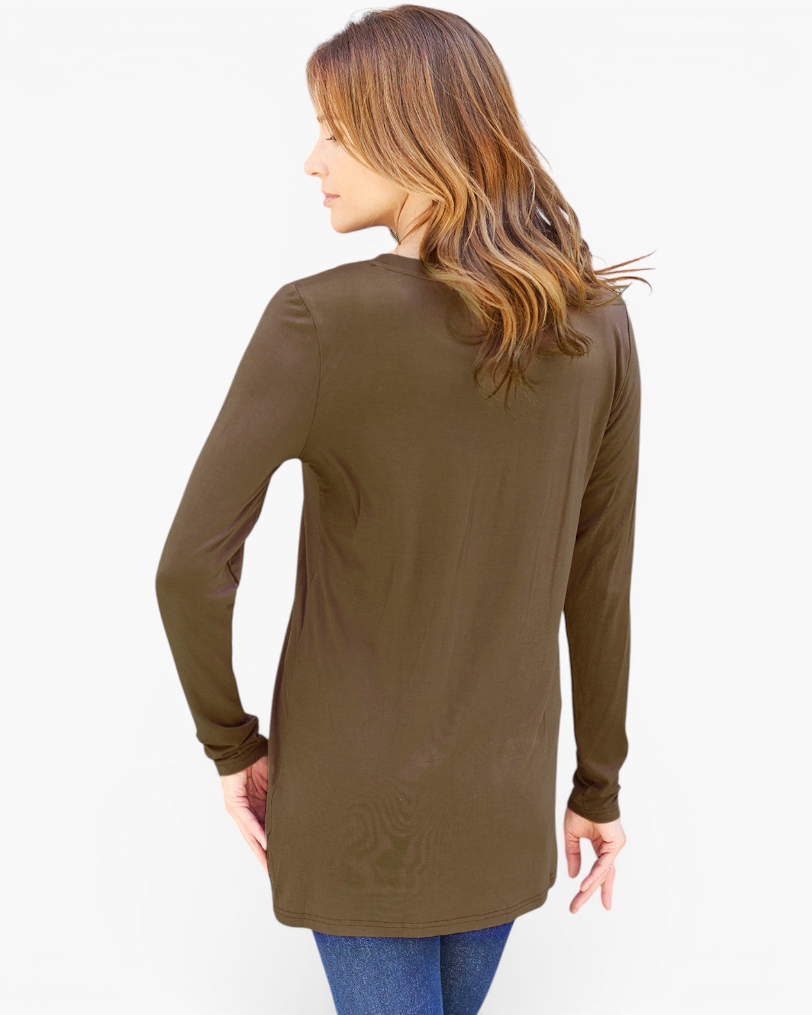 A woman shown from the back wearing a long-sleeve olive brown tunic top with blue jeans, photographed against a plain white studio background.