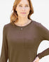 A woman wearing a brown long-sleeve crewneck top with a chest pocket, shown against a plain light background.