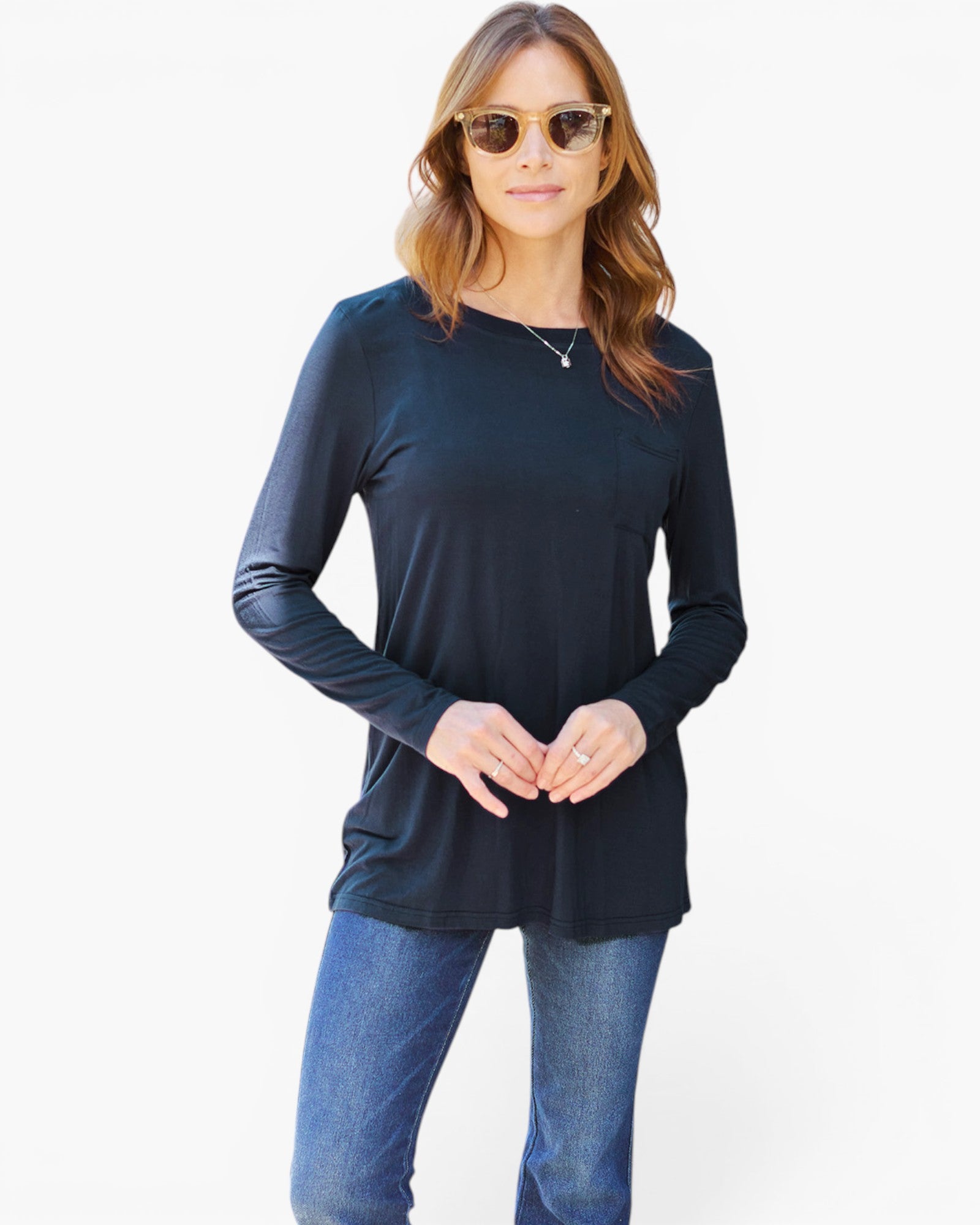A woman modeling a dark navy blue long-sleeve top with a crew neck, paired with blue jeans, against a plain white studio background.